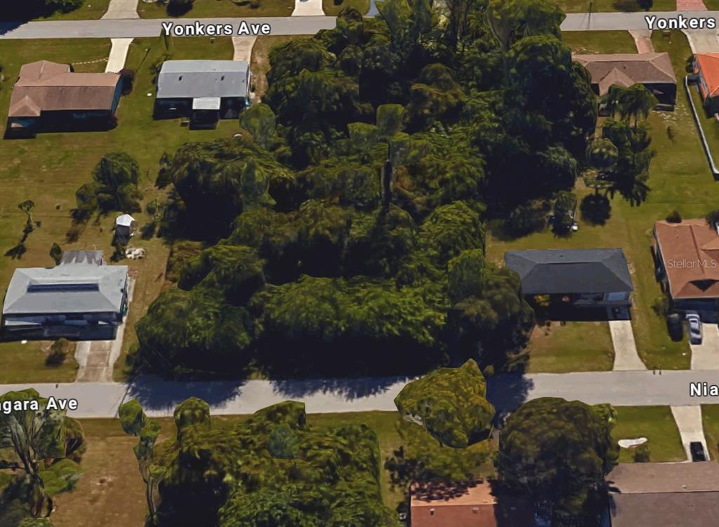 An aerial view shows a heavily wooded vacant lot situated between several residential houses — 22313 NIAGARA AVENUE, PORT CHARLOTTE, FL