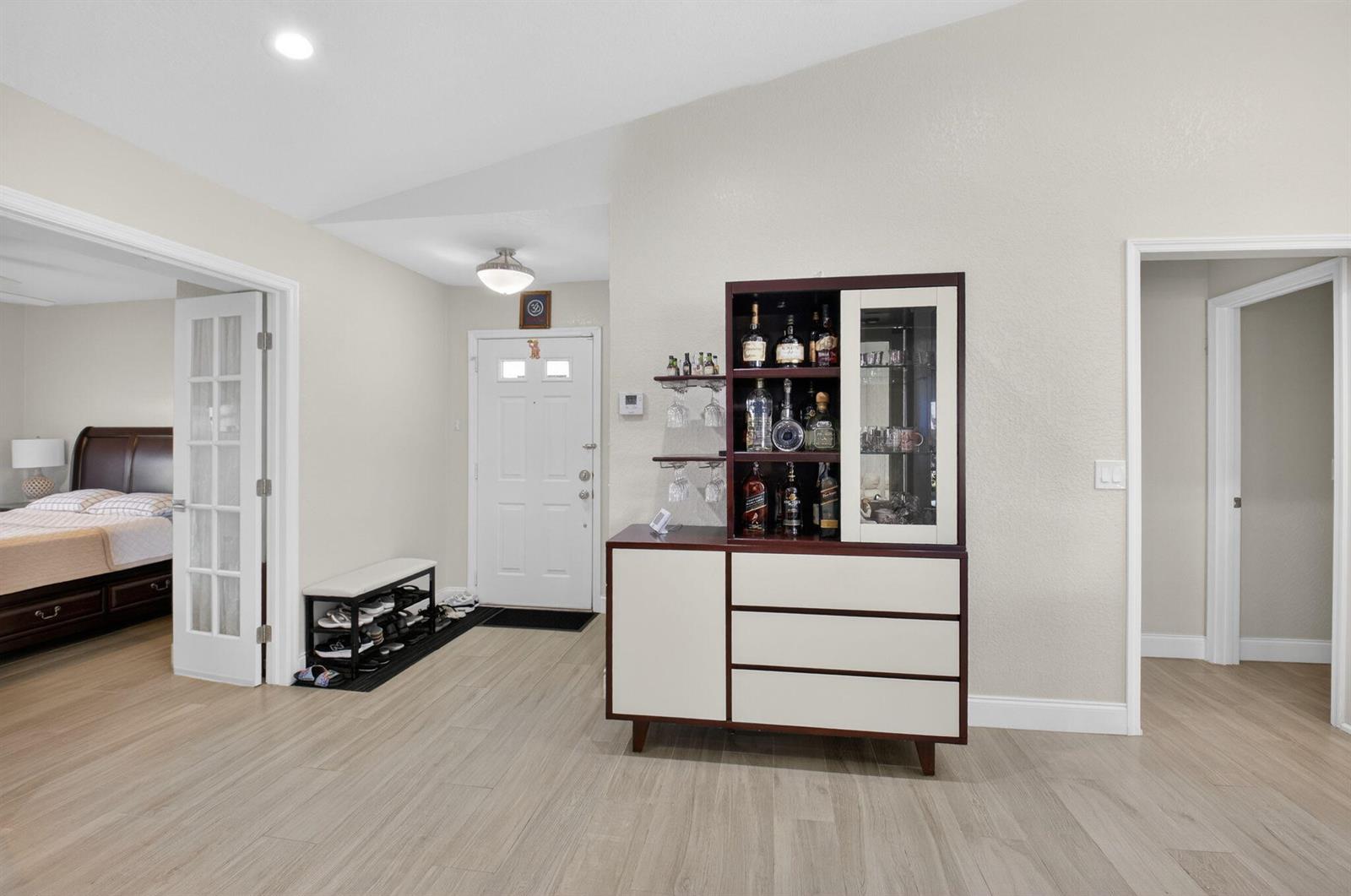 A foyer features light wood-look flooring, a white front door, and a modern bar cabinet — 5750 Parkwalk Circle E, Boynton Beach FL 33472, BOYNTON BEACH, FL