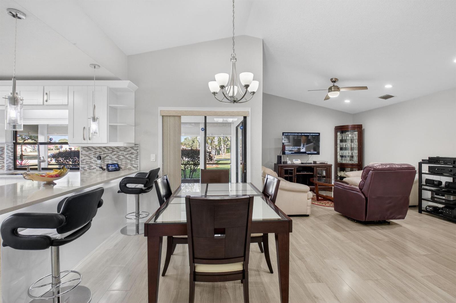 A dining area and living room with light wood flooring, white cabinets, and a chandelier — 5750 Parkwalk Circle E, Boynton Beach FL 33472, BOYNTON BEACH, FL