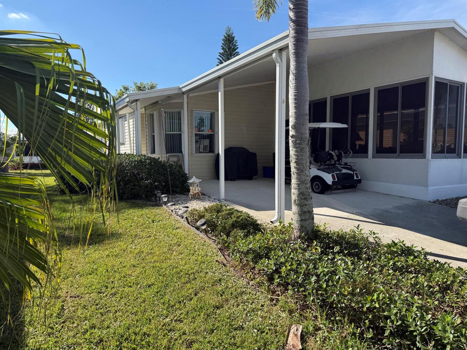 A single-story home features a covered carport, a screened-in porch, and a landscaped front yard — 6615 Spanish Lakes Boulevard, Fort Pierce FL 34951, FORT PIERCE, FL