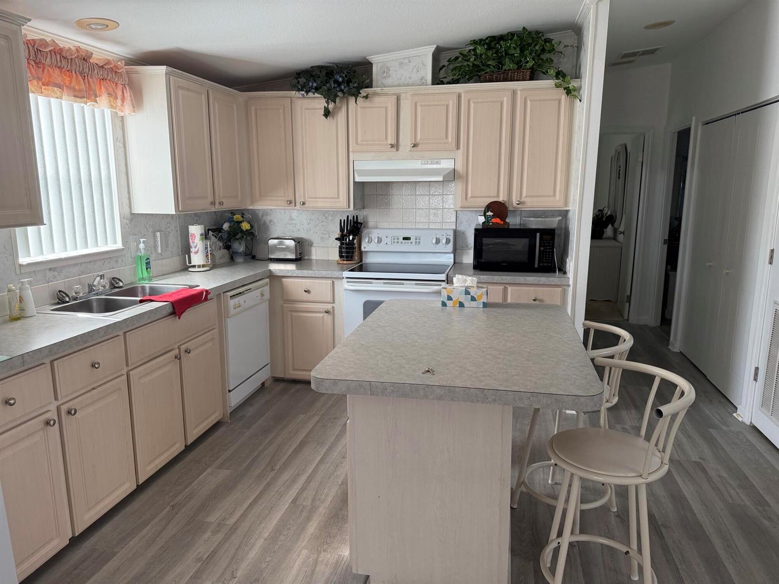 A kitchen features light wood cabinets, gray laminate countertops, white appliances, and wood-look flooring — 6615 Spanish Lakes Boulevard, Fort Pierce FL 34951, FORT PIERCE, FL