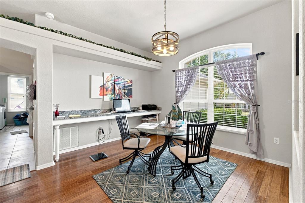 A dining area with a glass table, black chairs, a patterned rug, and built-in desk — 5287 SLATER ROAD, SPRING HILL, FL