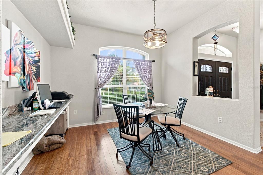 A dining area with a built-in desk, glass table, and hardwood floors near an entryway — 5287 SLATER ROAD, SPRING HILL, FL