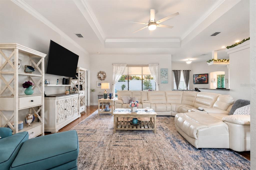A spacious living room features a large white sectional sofa, a patterned rug, and a television — 5287 SLATER ROAD, SPRING HILL, FL
