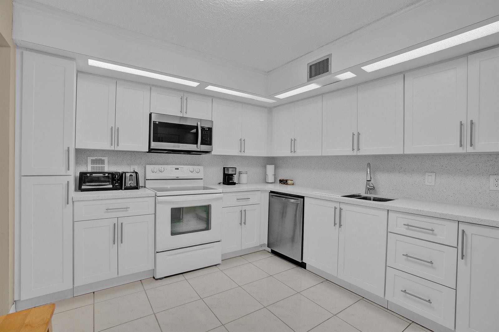 A kitchen with white cabinets, stainless steel appliances, and light-colored tile flooring — 2800 N 46th Avenue # A302, Hollywood FL 33021, HOLLYWOOD, FL