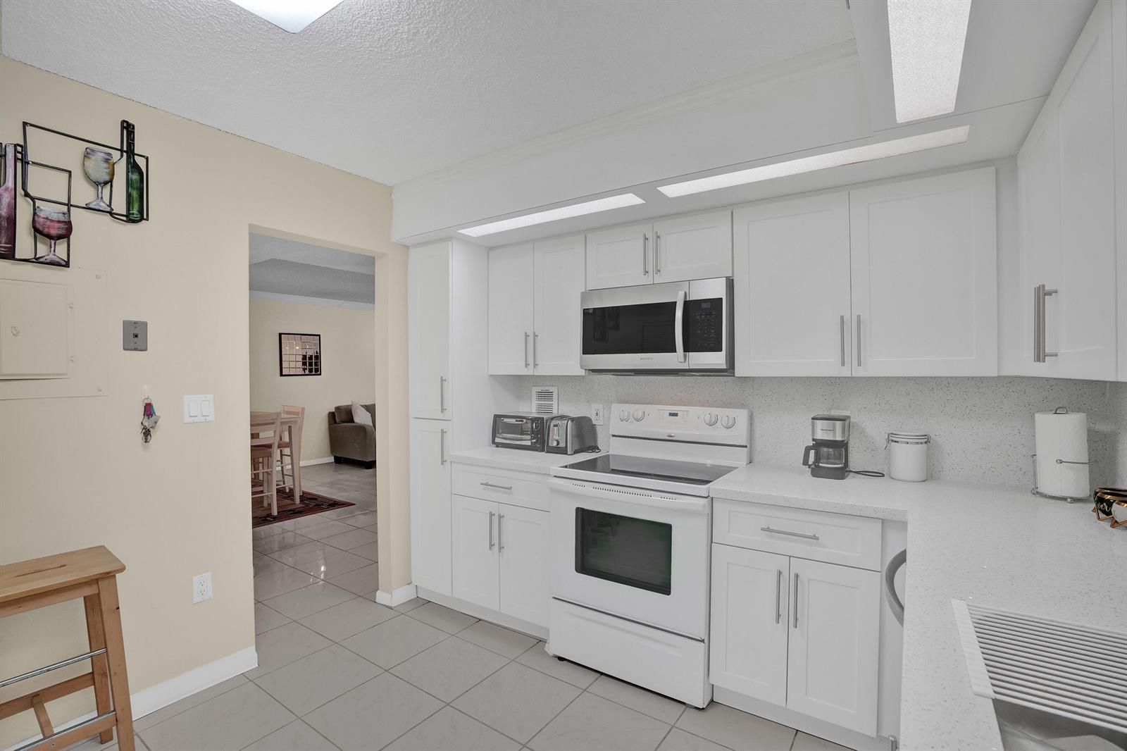 A kitchen with white cabinets, white appliances, and light-colored tile flooring — 2800 N 46th Avenue # A302, Hollywood FL 33021, HOLLYWOOD, FL