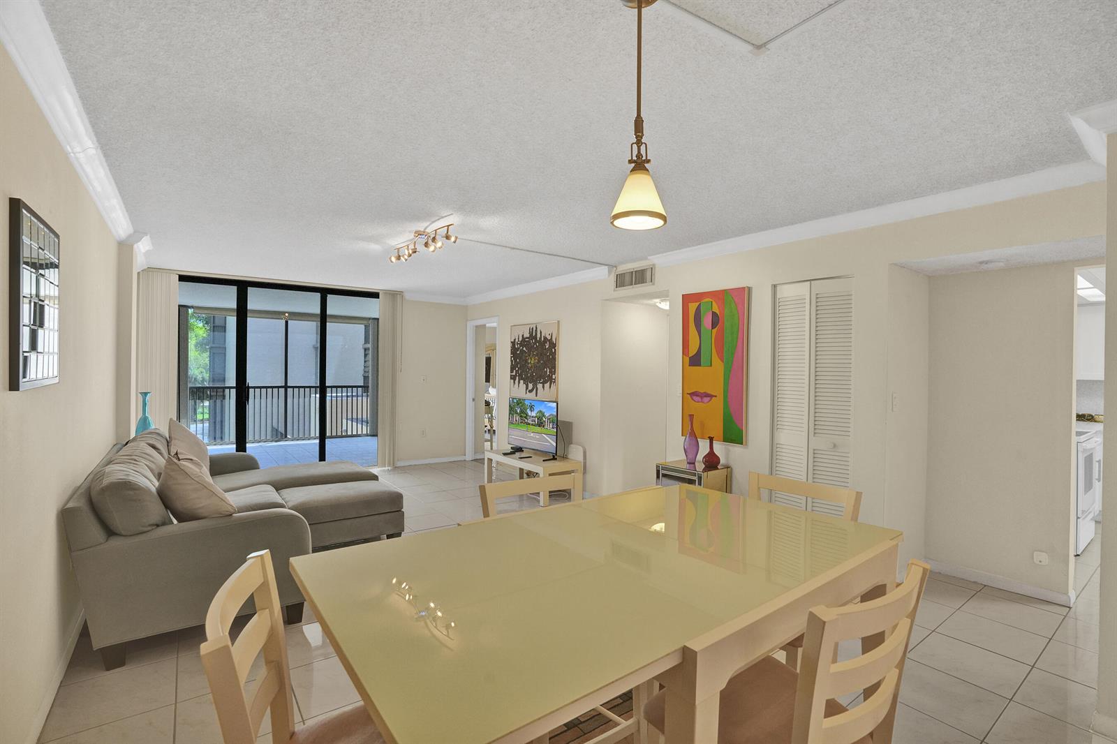 A dining area with a glass-top table leads into a living room with a balcony — 2800 N 46th Avenue # A302, Hollywood FL 33021, HOLLYWOOD, FL