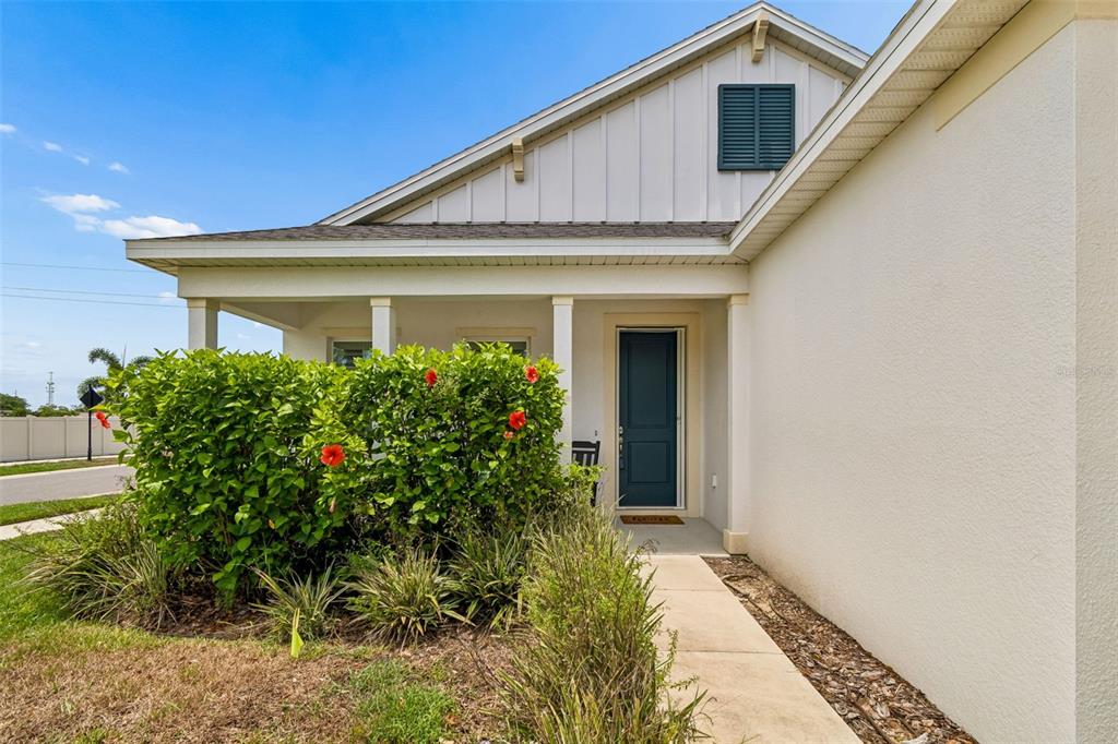 The exterior view shows a house entrance with a covered porch, landscaping, and a walkway — 283 SAND CRANE WAY, TARPON SPRINGS, FL