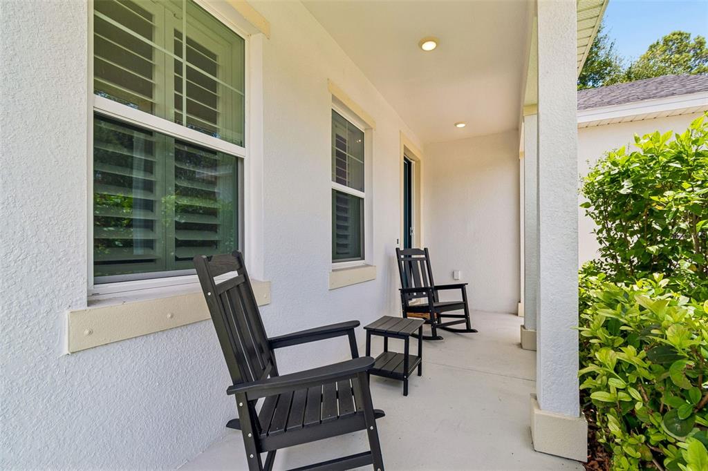 A covered front porch features two black rocking chairs and a small matching side table — 283 SAND CRANE WAY, TARPON SPRINGS, FL