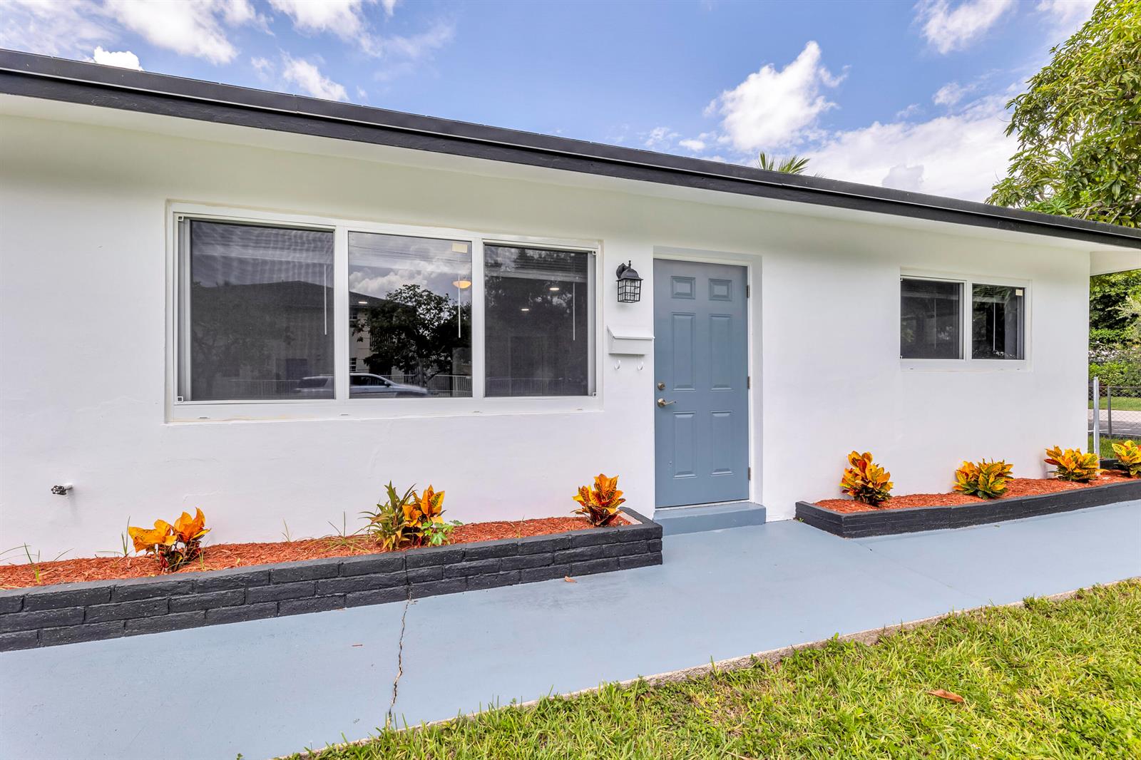 A white house exterior features a blue front door, large windows, and black planter boxes — 800-802 SW 6th Court, Pompano Beach FL 33060, POMPANO BEACH, FL