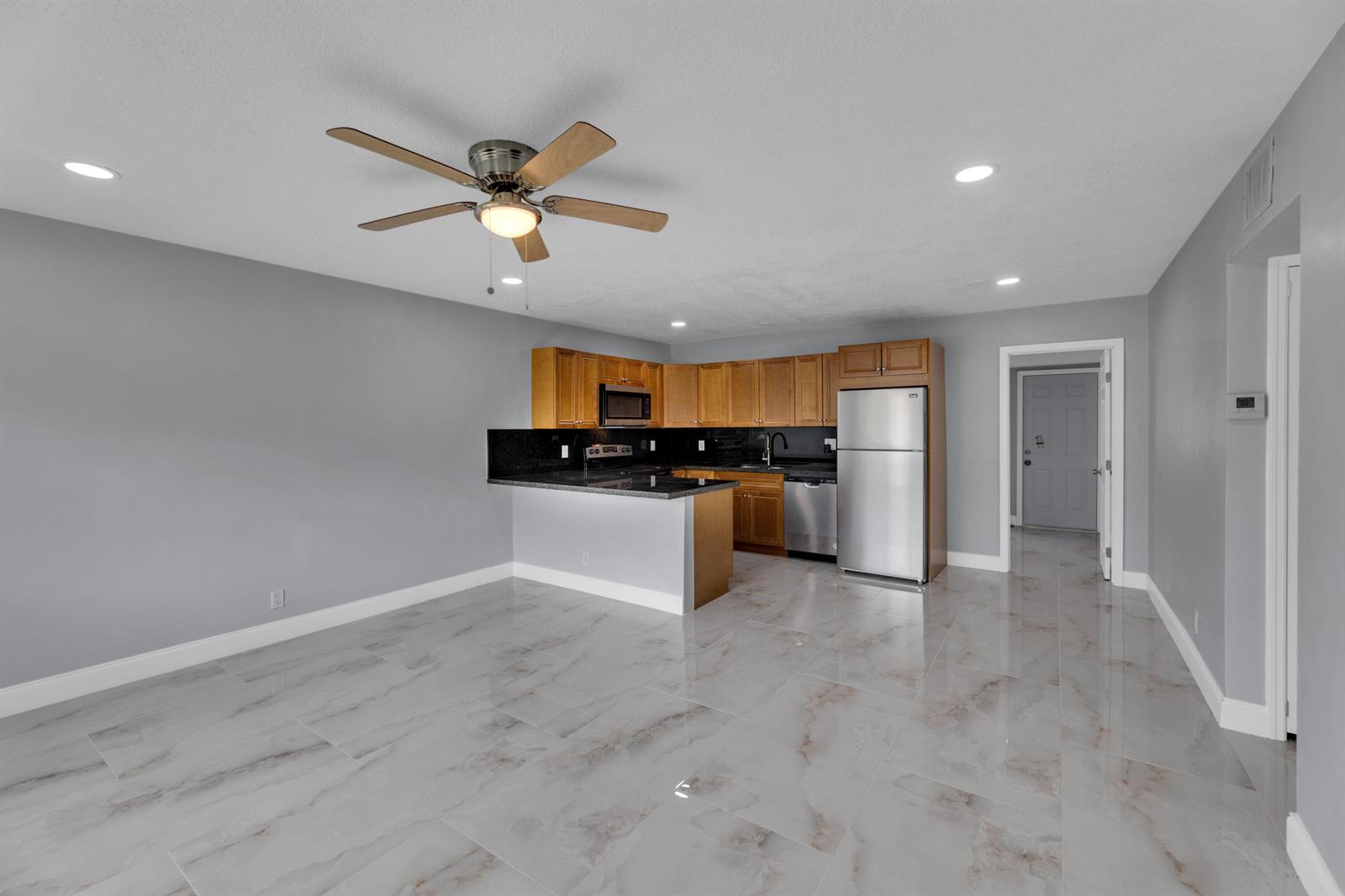 A kitchen with wood cabinets and a breakfast bar opens to a gray-walled living area — 800-802 SW 6th Court, Pompano Beach FL 33060, POMPANO BEACH, FL