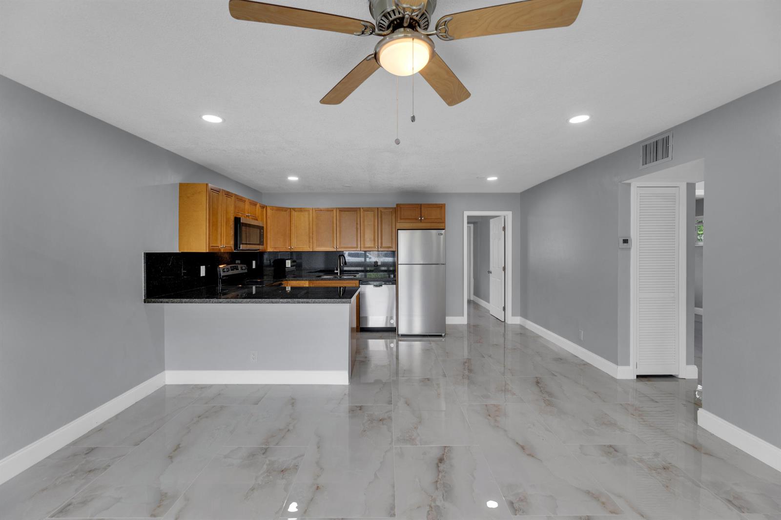 A kitchen with wood cabinets, black countertops, stainless steel appliances, and light-colored tiled flooring — 800-802 SW 6th Court, Pompano Beach FL 33060, POMPANO BEACH, FL