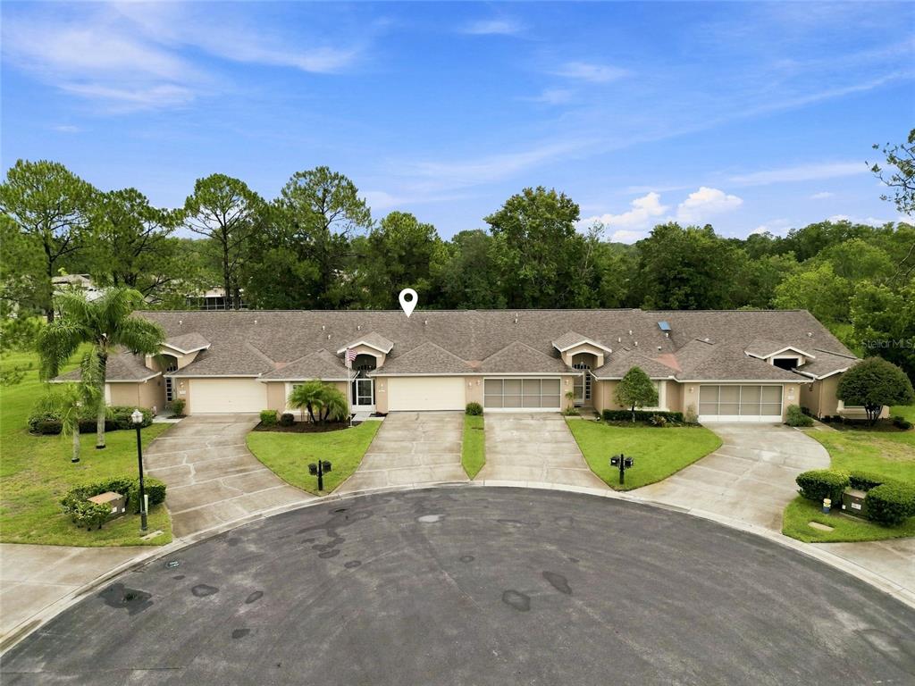 An aerial view shows a row of attached single-story townhomes with garages and driveways — 7411 MOORGATE COURT, NEW PORT RICHEY, FL