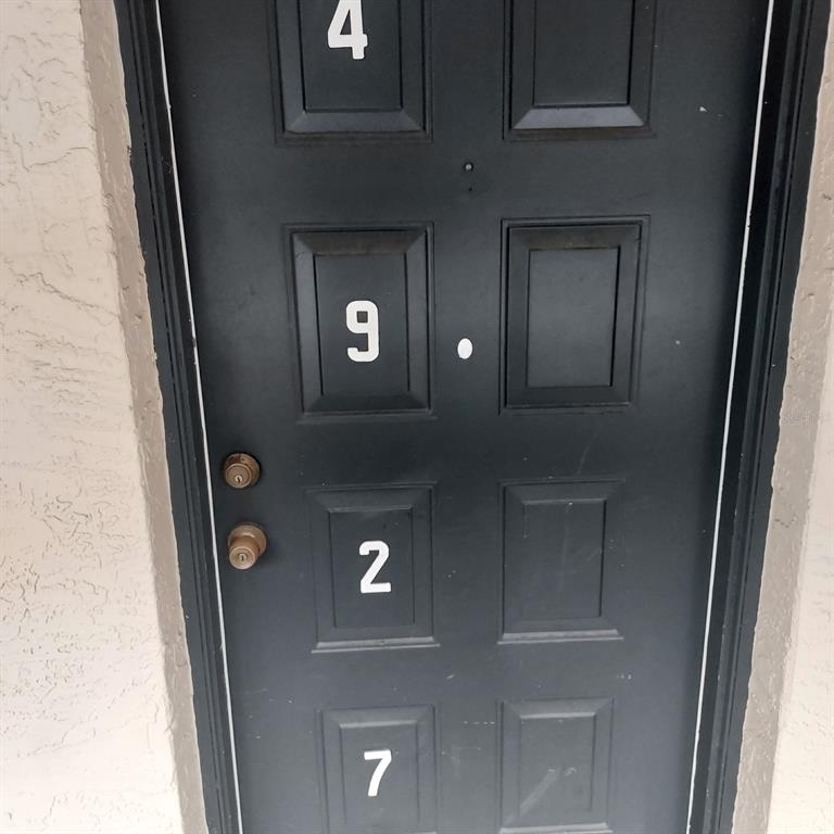 A black door features the numbers 4, 9, 2, and 7 applied to its panels — 4927 PURITAN CIRCLE UNIT 123, TAMPA, FL