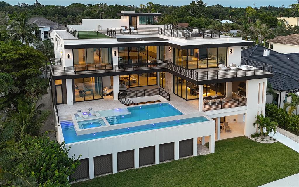 A modern multi-story house with a large infinity pool, multiple balconies, and a rooftop terrace — 388 S SHORE DRIVE, SARASOTA, FL