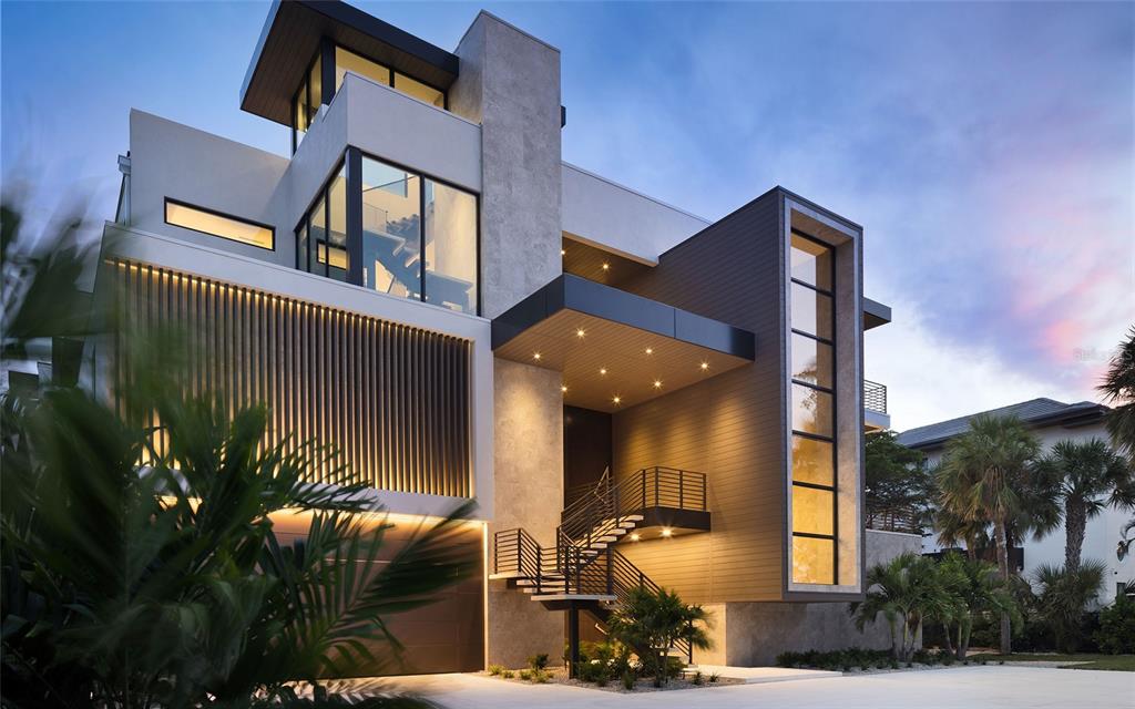 A modern three-story house features a prominent staircase, wood-paneled accents, and large glass windows — 388 S SHORE DRIVE, SARASOTA, FL