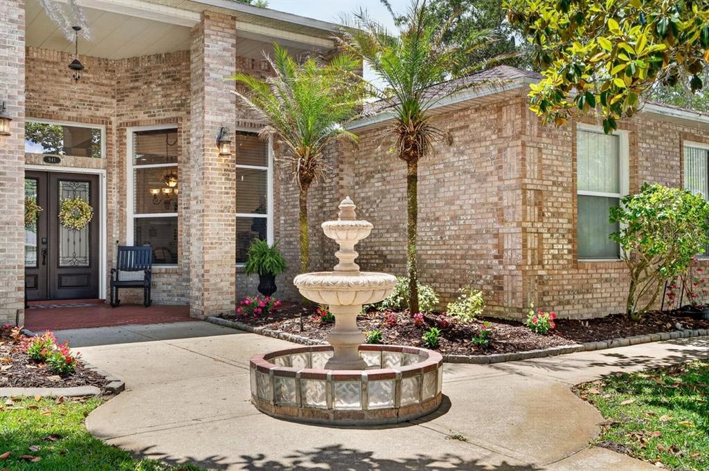 A brick house exterior features a tiered stone fountain in the front garden walkway — 941 GEORGE HECKER DRIVE, SOUTH DAYTONA, FL