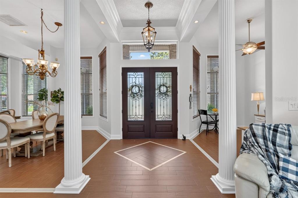 A foyer with wood-look tile flooring, white columns, and a double front door — 941 GEORGE HECKER DRIVE, SOUTH DAYTONA, FL