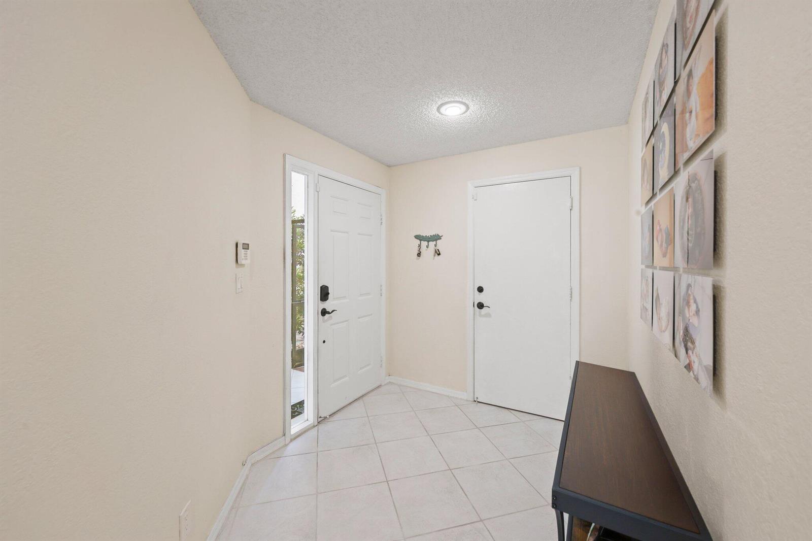 An entryway features a white front door, tiled floors, a console table, and wall art — 8634 Via Reale # 3, Boca Raton FL 33496, BOCA RATON, FL