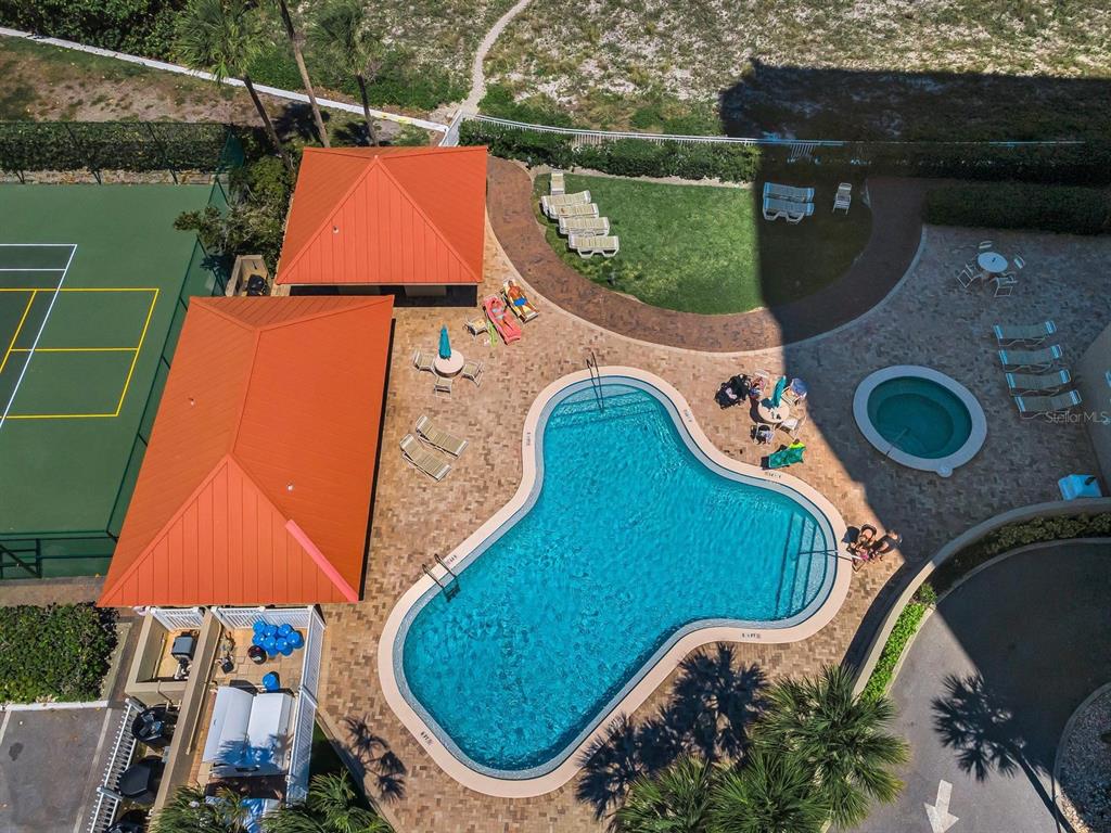 An aerial view shows a swimming pool, hot tub, tennis court, and two buildings — 1290 GULF BOULEVARD UNIT 2003, CLEARWATER BEACH, FL
