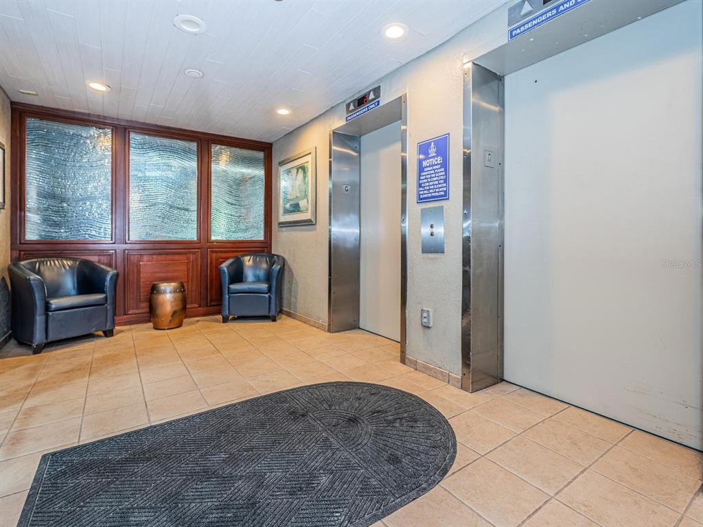 An elevator lobby with two elevators, two leather chairs, and a textured rug on tile — 1290 GULF BOULEVARD UNIT 2003, CLEARWATER BEACH, FL
