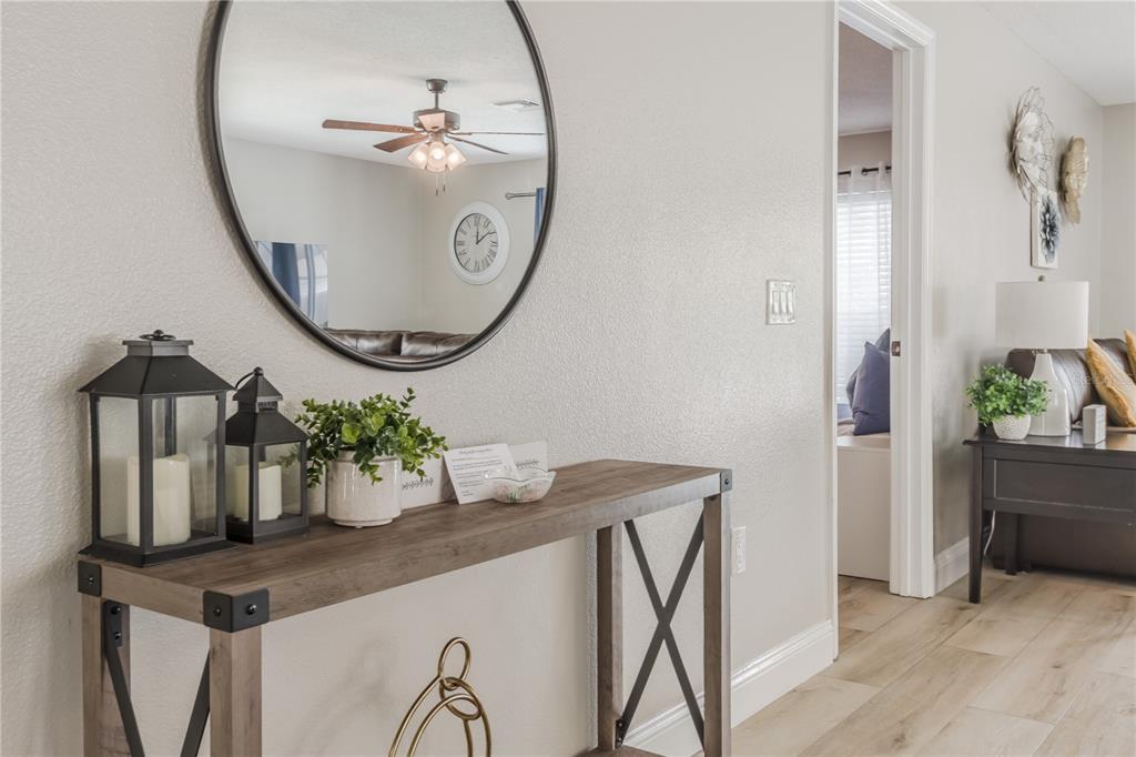 A console table with lanterns and a mirror sits in a hallway near a doorway — 4609 FORMBY COURT, KISSIMMEE, FL
