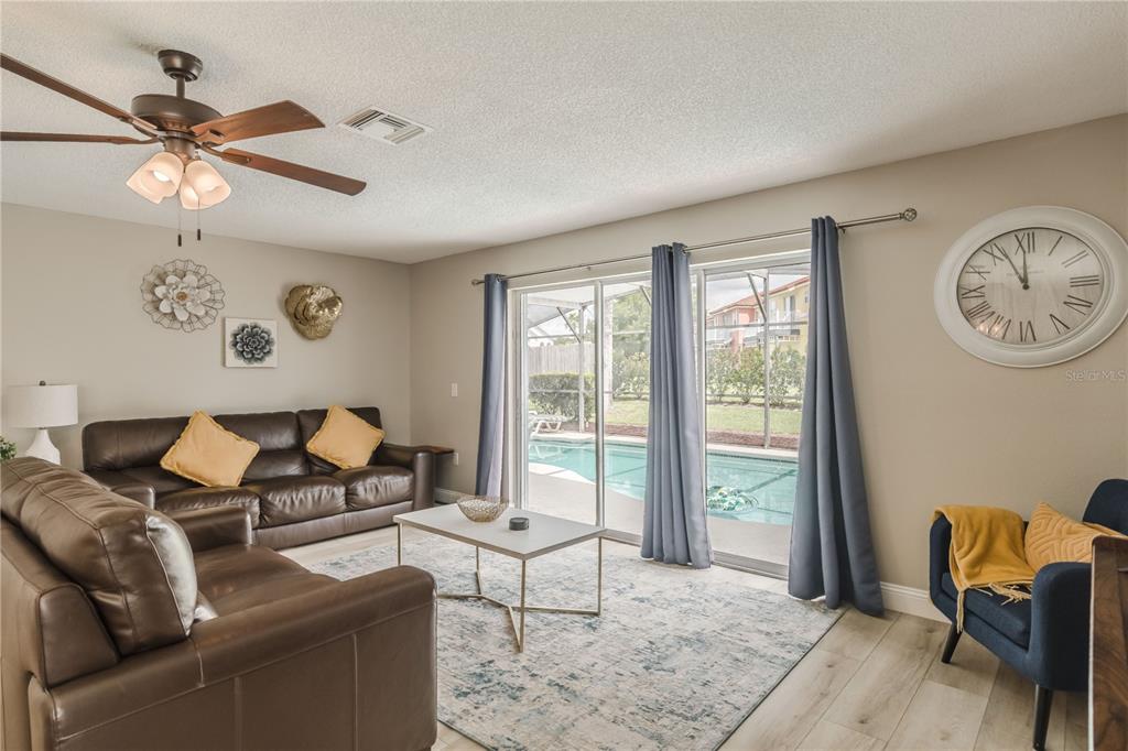 A living room features brown leather sofas, a coffee table, and sliding doors overlooking a pool — 4609 FORMBY COURT, KISSIMMEE, FL