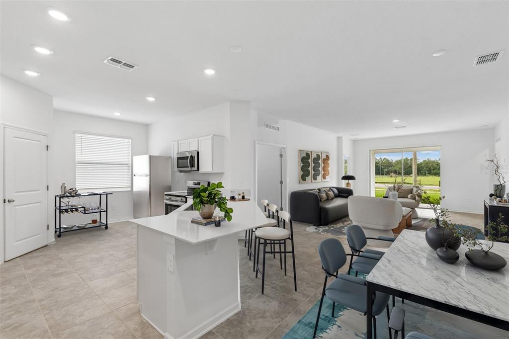 An open-concept kitchen and living area with white cabinets, a kitchen island, and tile flooring — 1676 TEAGAN LANE, WINTER HAVEN, FL
