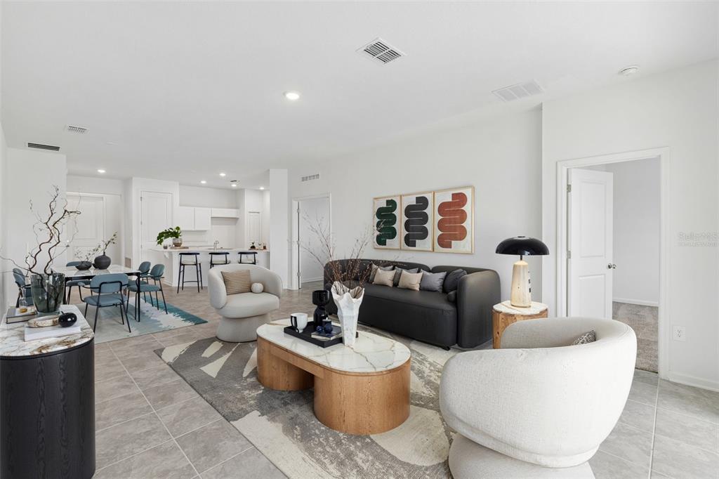 An open-concept living and dining area features a modern sofa, two armchairs, and tile flooring — 1676 TEAGAN LANE, WINTER HAVEN, FL