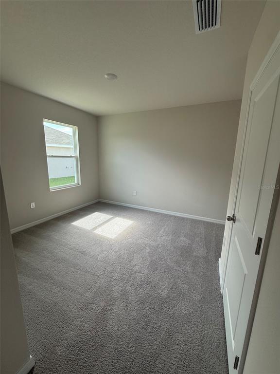 An empty bedroom with beige walls, gray carpet, and a single window — 11003 44TH AVENUE E, PALMETTO, FL