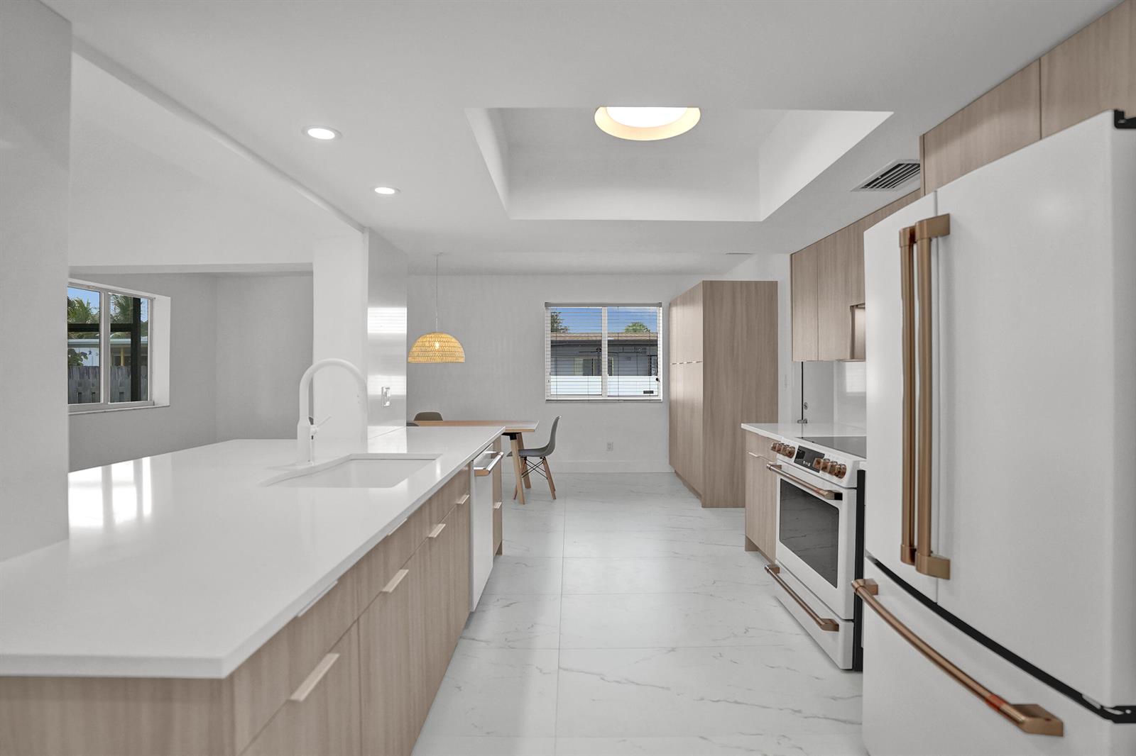 A modern kitchen features light wood cabinets, white countertops, stainless steel appliances, and tile flooring — 2030 N 54th Avenue, Hollywood FL 33021, HOLLYWOOD, FL