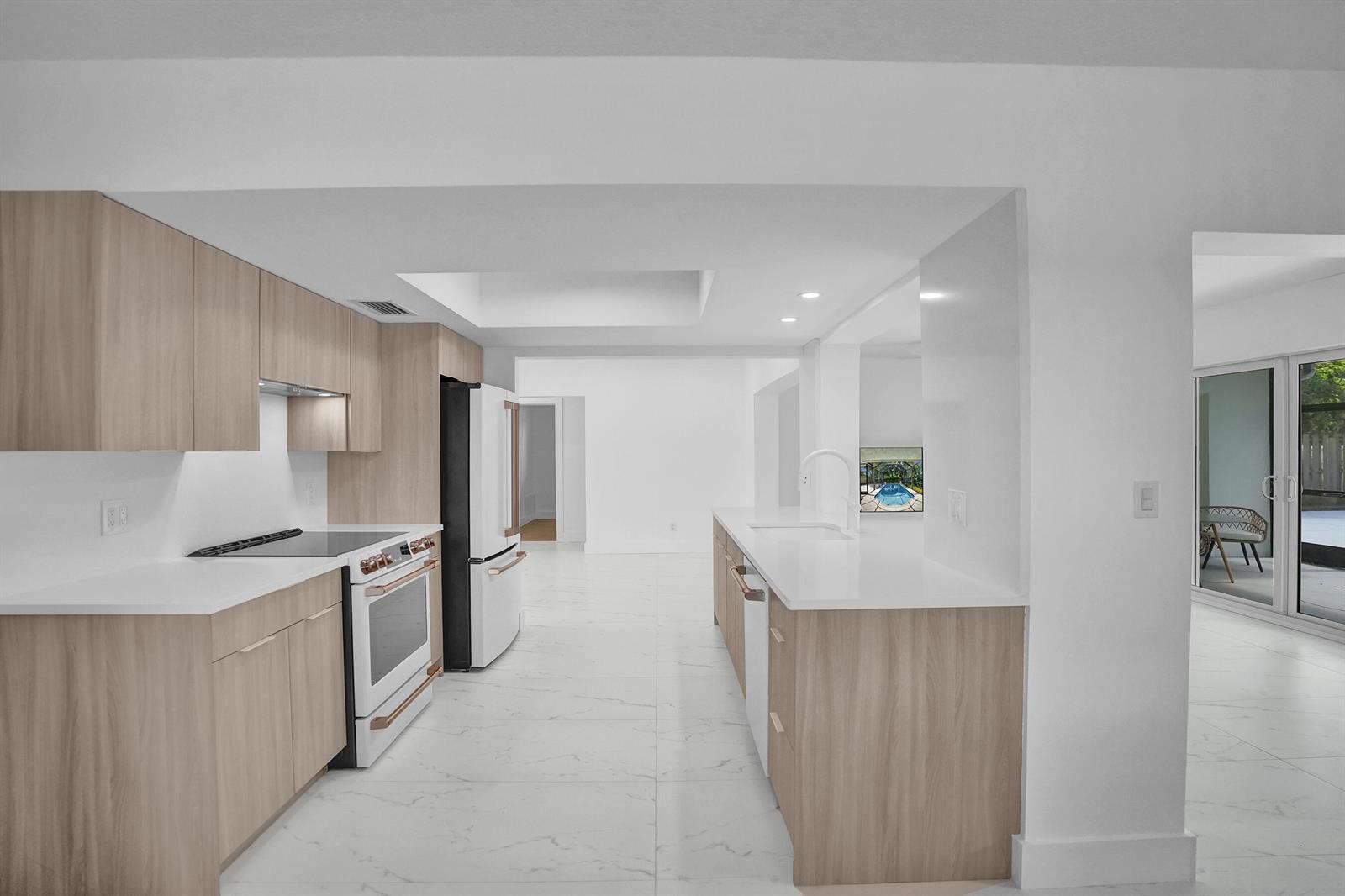 A modern kitchen features light wood cabinets, white countertops, and stainless steel appliances — 2030 N 54th Avenue, Hollywood FL 33021, HOLLYWOOD, FL