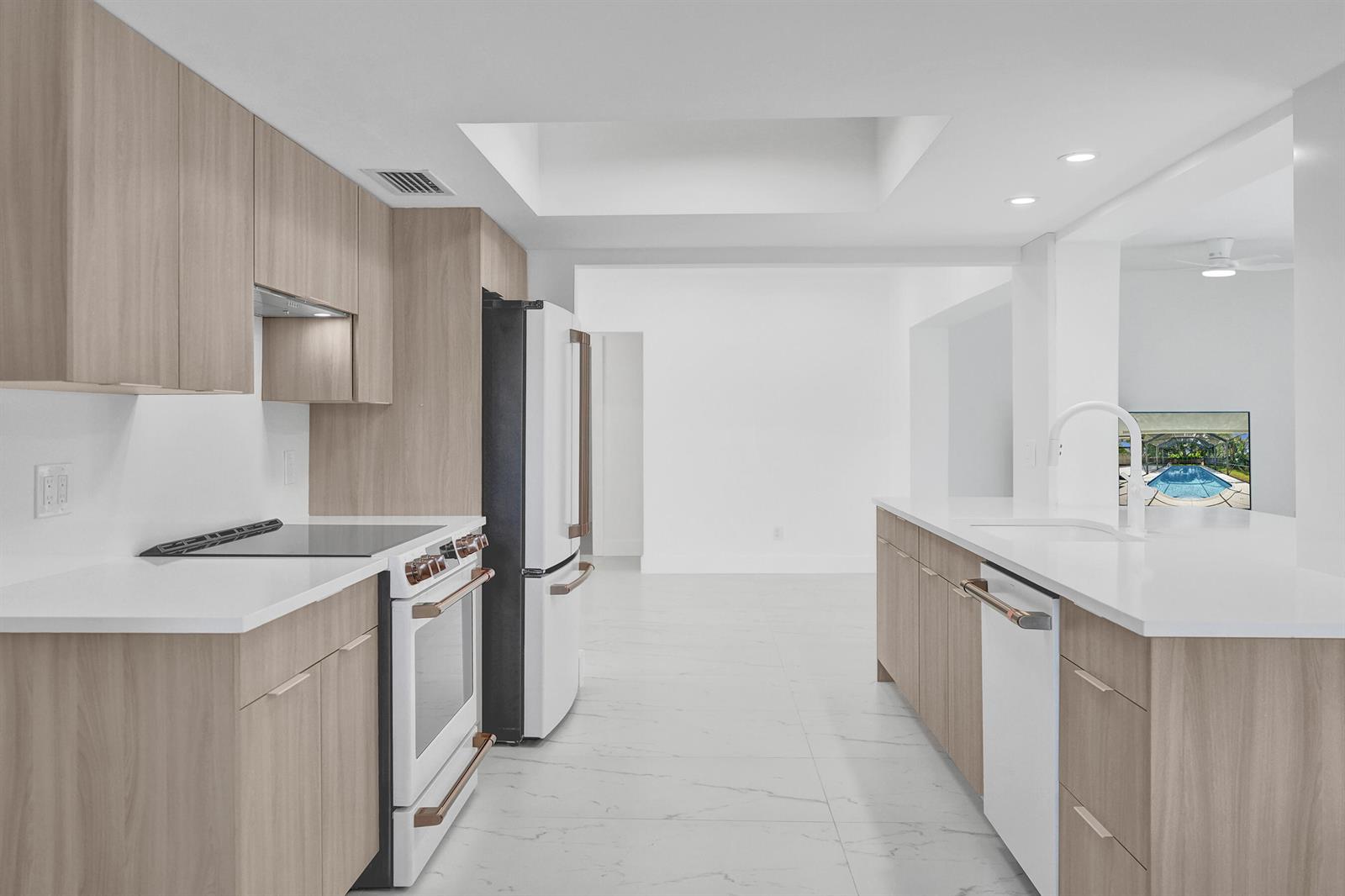 A modern kitchen features light wood cabinets, white countertops, and white appliances with copper handles — 2030 N 54th Avenue, Hollywood FL 33021, HOLLYWOOD, FL