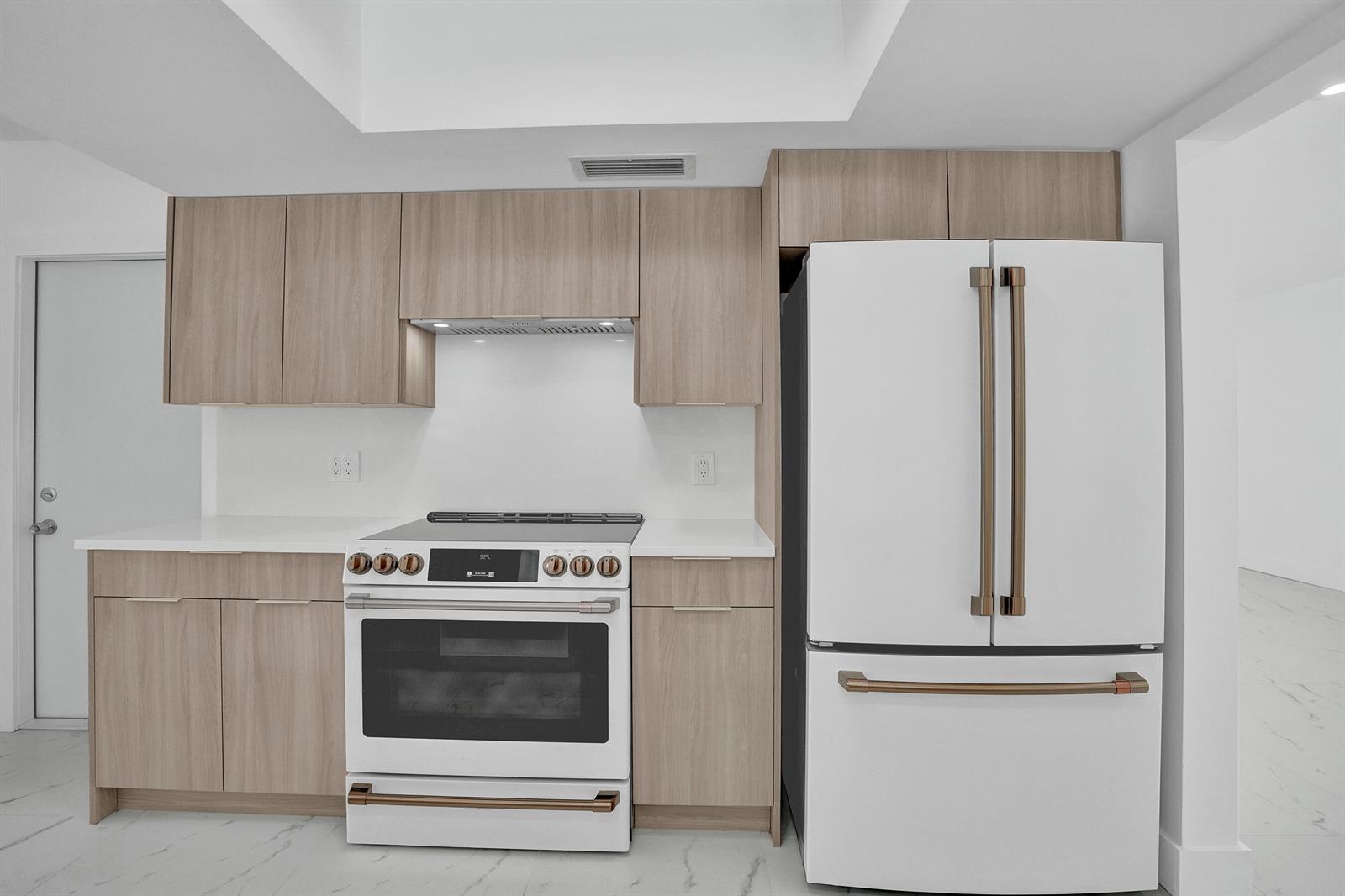 A kitchen features light wood cabinets, white countertops, and white appliances with bronze-toned hardware — 2030 N 54th Avenue, Hollywood FL 33021, HOLLYWOOD, FL