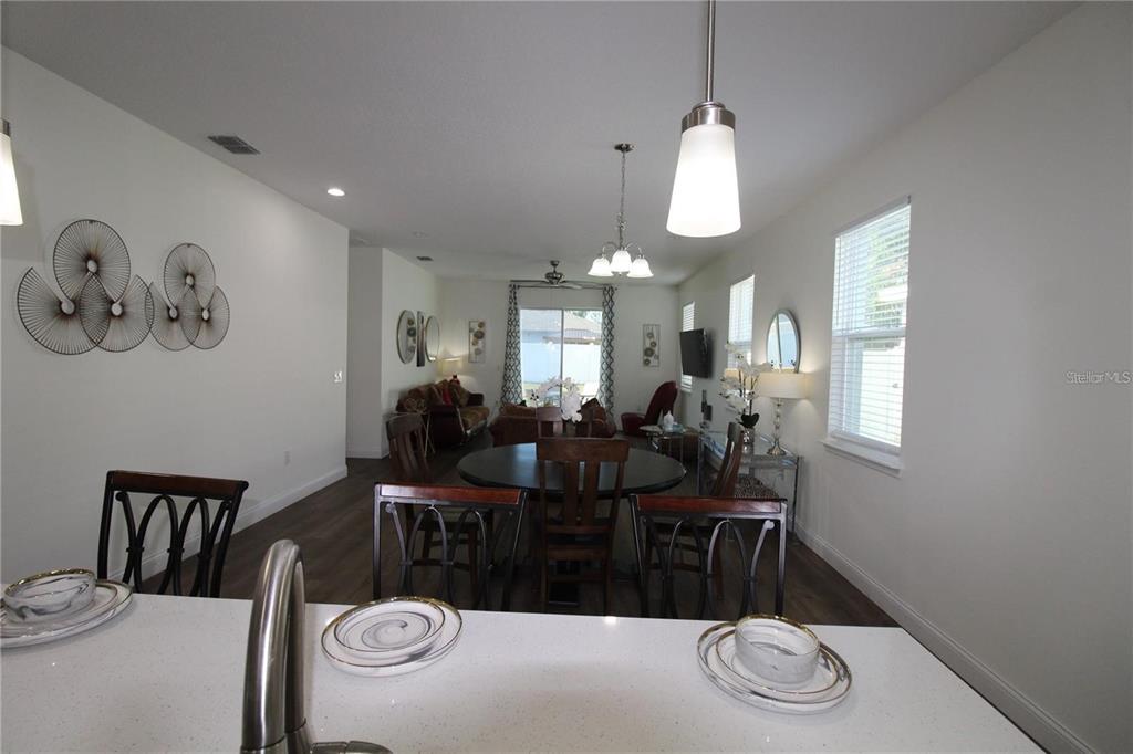 A kitchen island overlooks a dining area and living room with dark wood-look flooring — 821 LAND AVENUE, LONGWOOD, FL