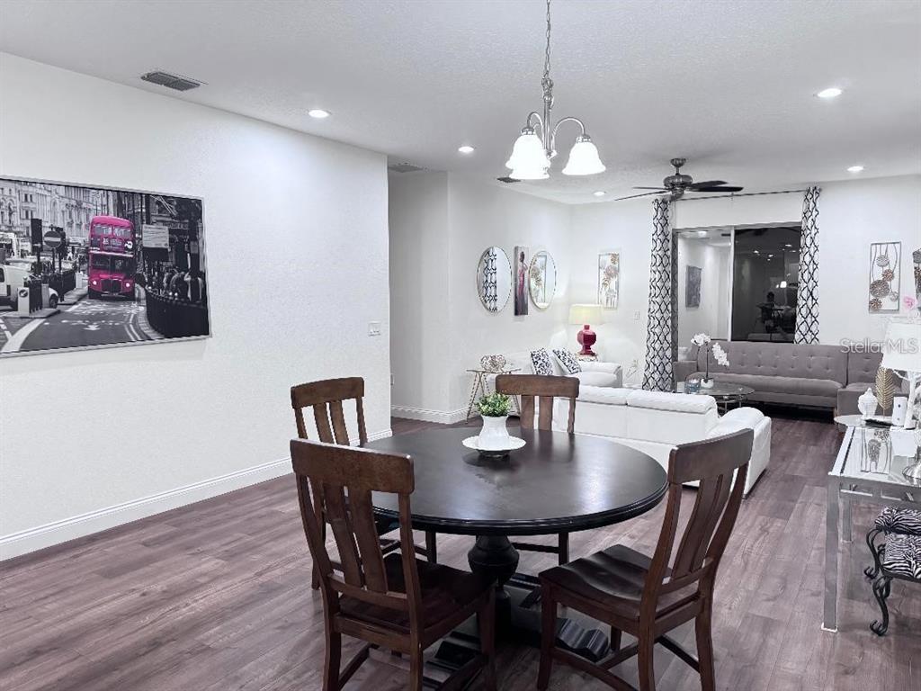A dining area with a round wooden table leads into a living room with white furniture — 821 LAND AVENUE, LONGWOOD, FL
