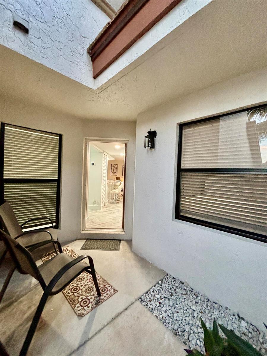 A small outdoor patio features two chairs, a doorway, and a gravel garden bed — 12692 Shoreline Drive # 3b, Wellington FL 33414, WELLINGTON, FL