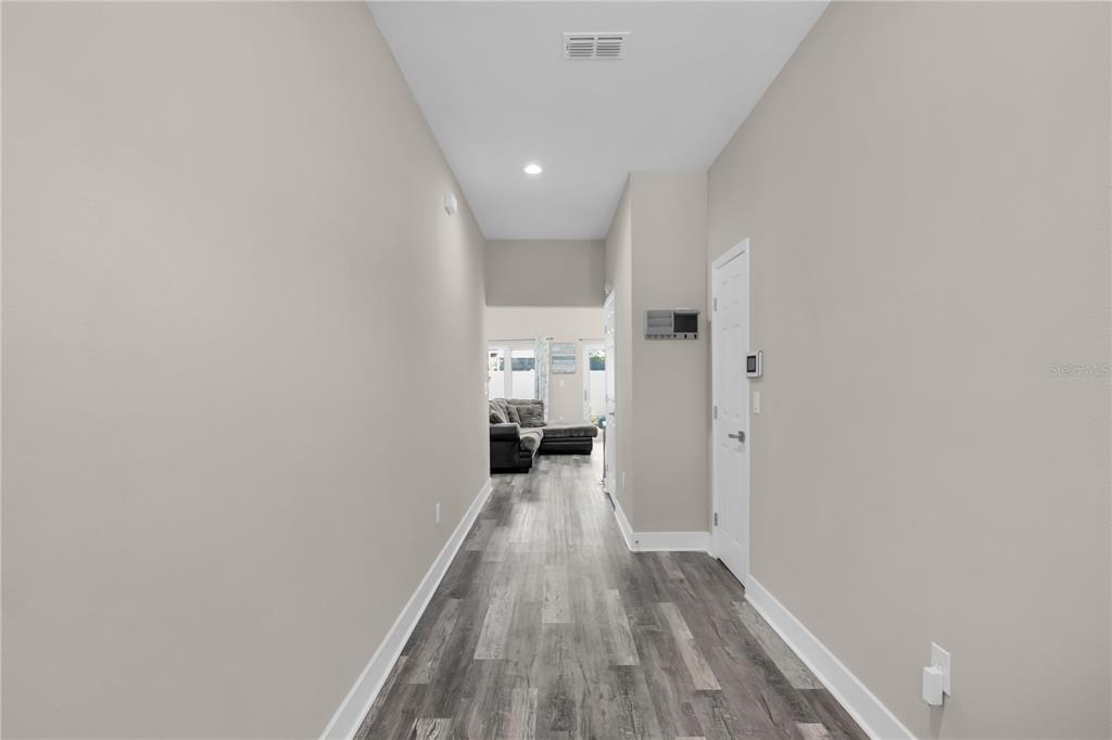A hallway with gray wood-look flooring leads toward a living area with a sofa — 2404 CASSELL, TAMPA, FL