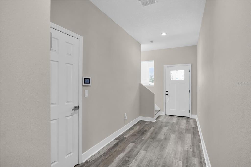 An entryway features light gray walls, wood-look flooring, a white door, and a closet door — 2404 CASSELL, TAMPA, FL