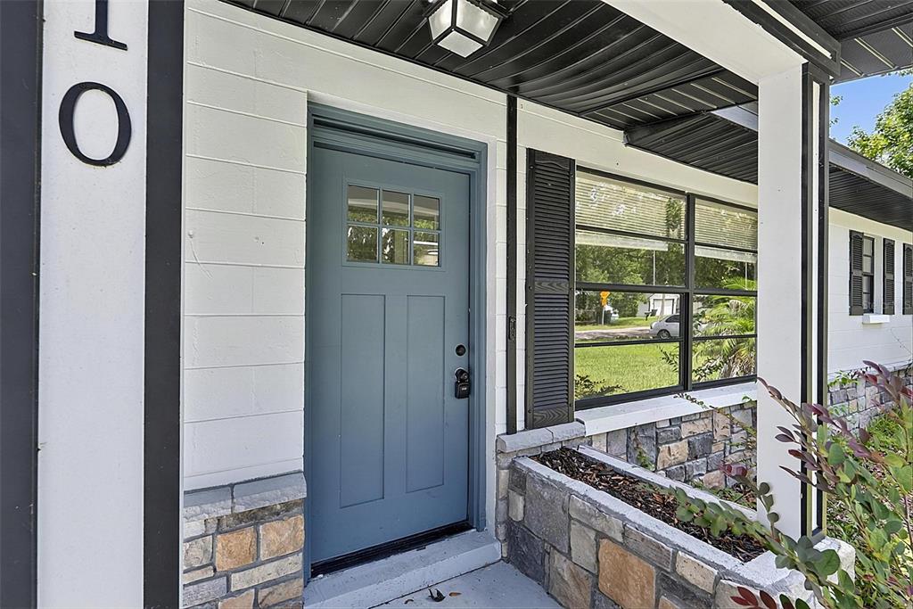 A blue front door sits next to a stone planter and a window with shutters — 610 ROMA STREET, DAYTONA BEACH, FL