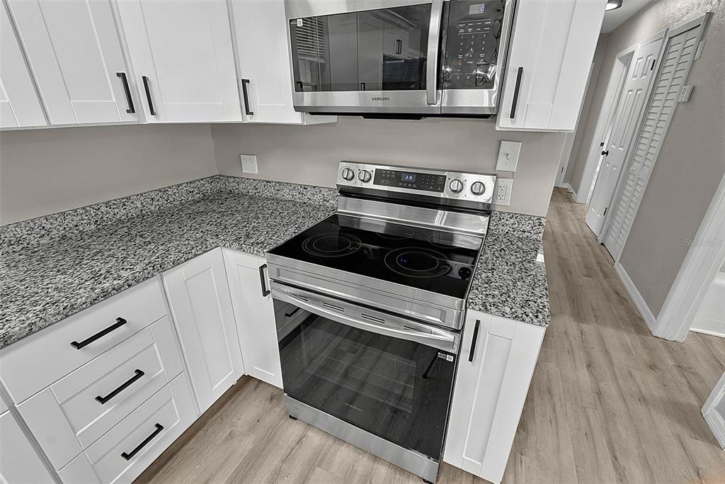 A kitchen features white cabinets, granite countertops, and stainless steel appliances — 610 ROMA STREET, DAYTONA BEACH, FL