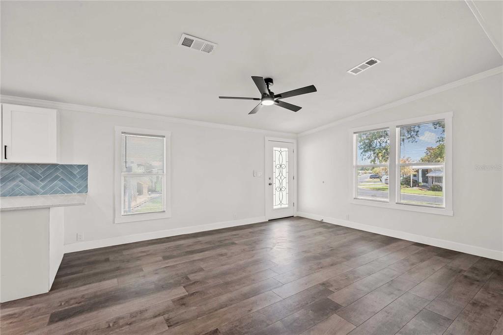 A bright living area features wood-look flooring, a ceiling fan, and a glass-paneled entry door — 34010 ESTATES LANE, WESLEY CHAPEL, FL