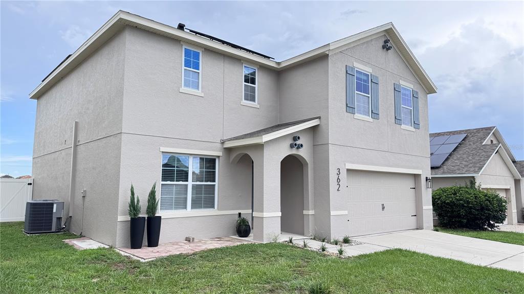 A two-story house with a beige stucco exterior, a two-car garage, and a front porch — 362 NOVA DRIVE, DAVENPORT, FL