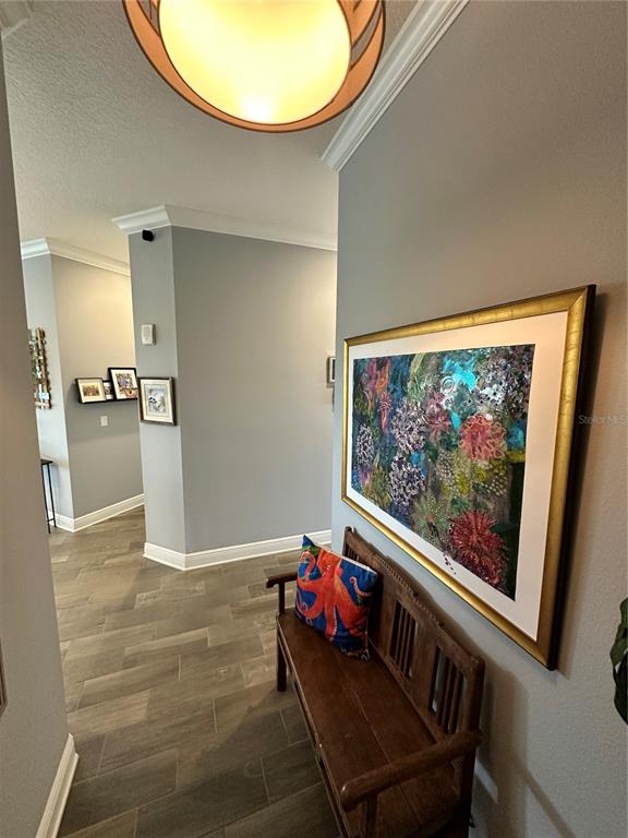 A hallway features tile flooring, a wooden bench, and a large framed floral painting — 7730 34TH AVE W UNIT 303, BRADENTON, FL