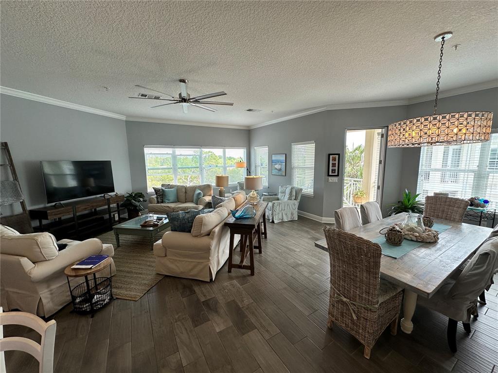 An open-concept living and dining area features gray walls, wood-look tile flooring, and large windows — 7730 34TH AVE W UNIT 303, BRADENTON, FL