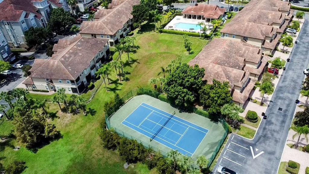 An aerial view shows a blue tennis court surrounded by apartment buildings and green space — 8755 THE ESPLANADE UNIT 130, ORLANDO, FL