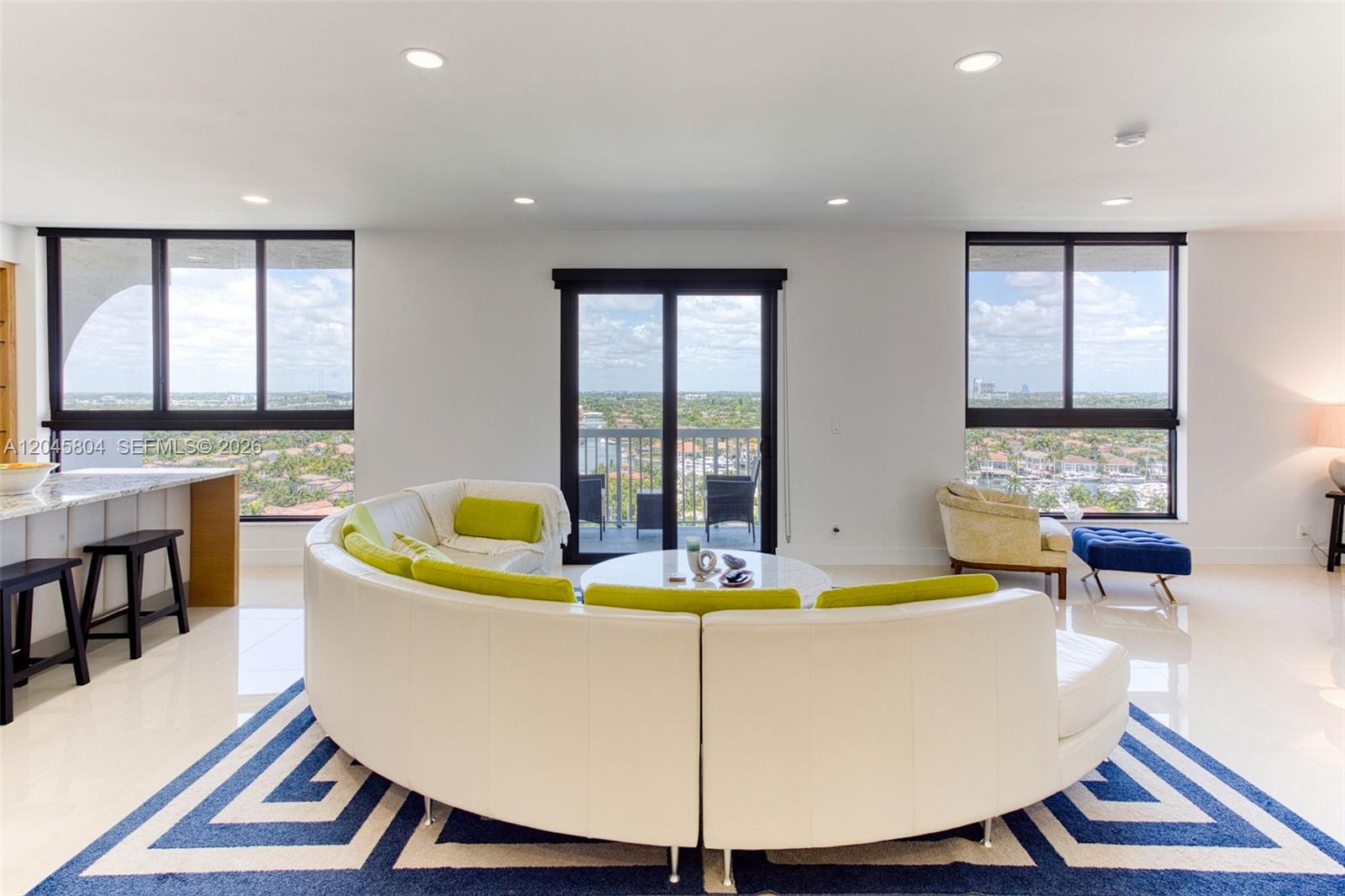 A living room features a curved white sofa, a geometric rug, and floor-to-ceiling windows — 1500 S Ocean Dr, Hollywood FL 33019, HOLLYWOOD, FL