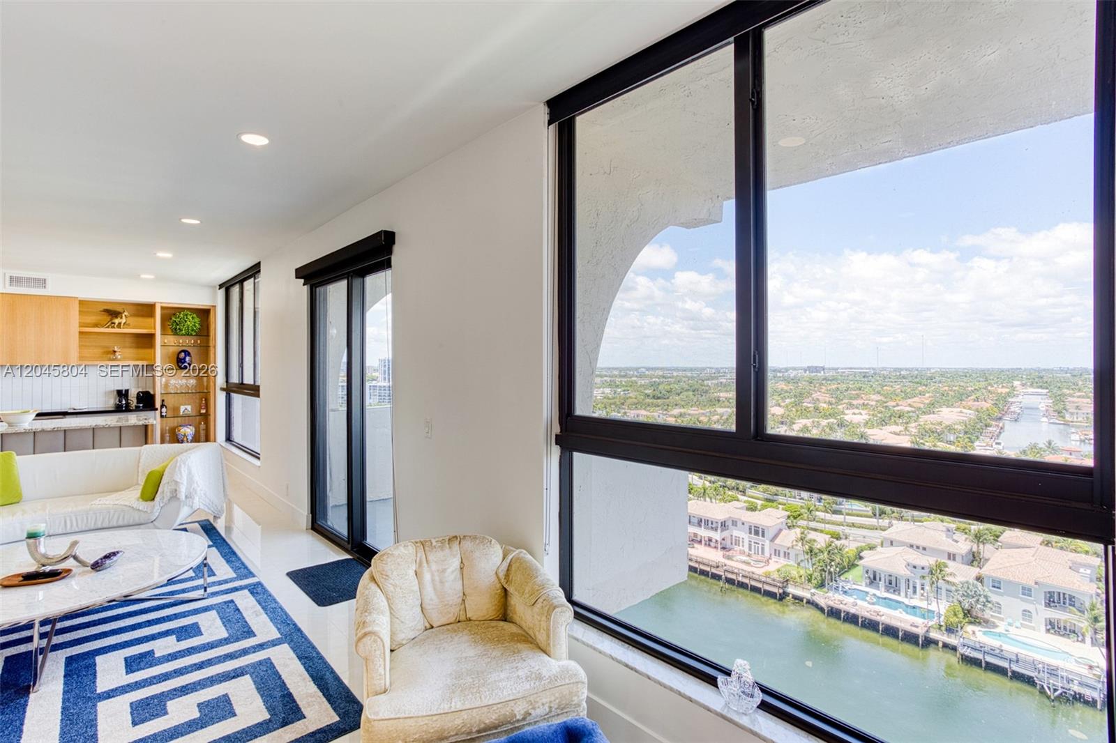 A living room with a white sofa, blue patterned rug, and floor-to-ceiling windows overlooking water — 1500 S Ocean Dr, Hollywood FL 33019, HOLLYWOOD, FL