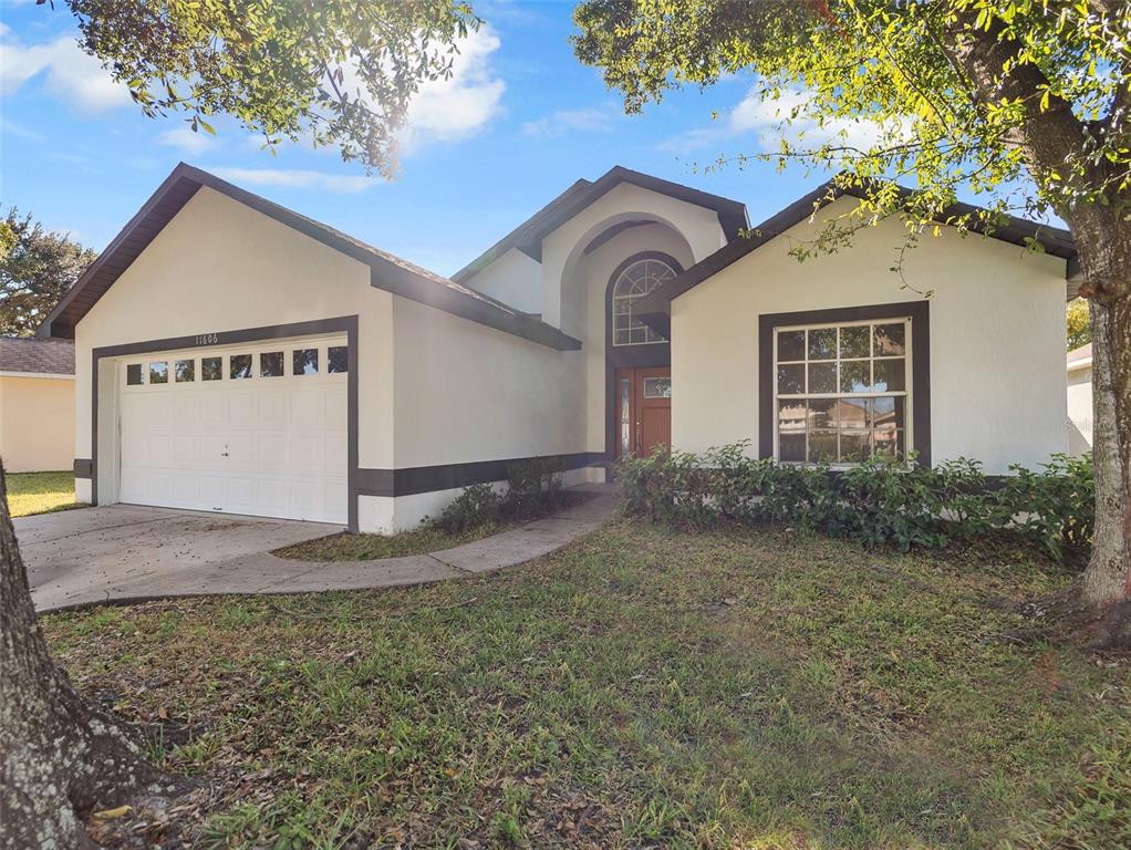 A single-story house with a white stucco exterior, dark trim, and a two-car garage — 11606 GOODWYCK DRIVE, ORLANDO, FL