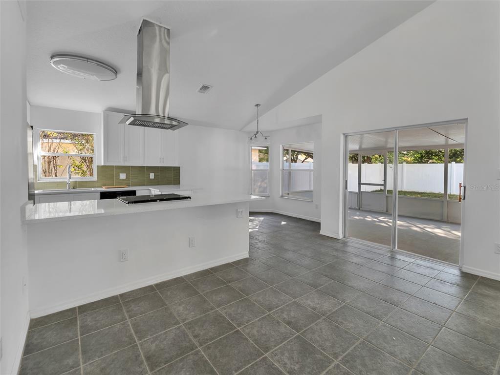 A kitchen with white cabinets, a stainless steel range hood, and gray tiled flooring — 11606 GOODWYCK DRIVE, ORLANDO, FL